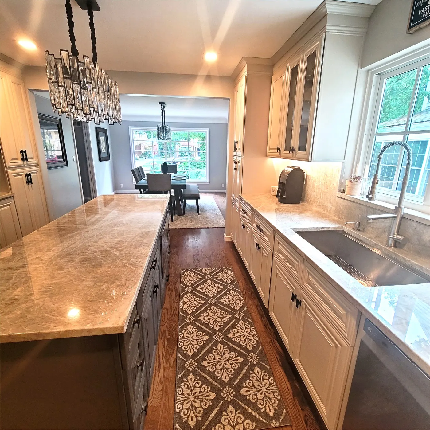 Kitchen after — cream cabinets, marble counters, patterned runner